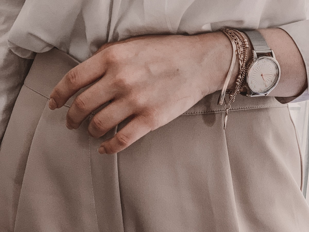 Silver bracelet and watch on wrist, white shirt